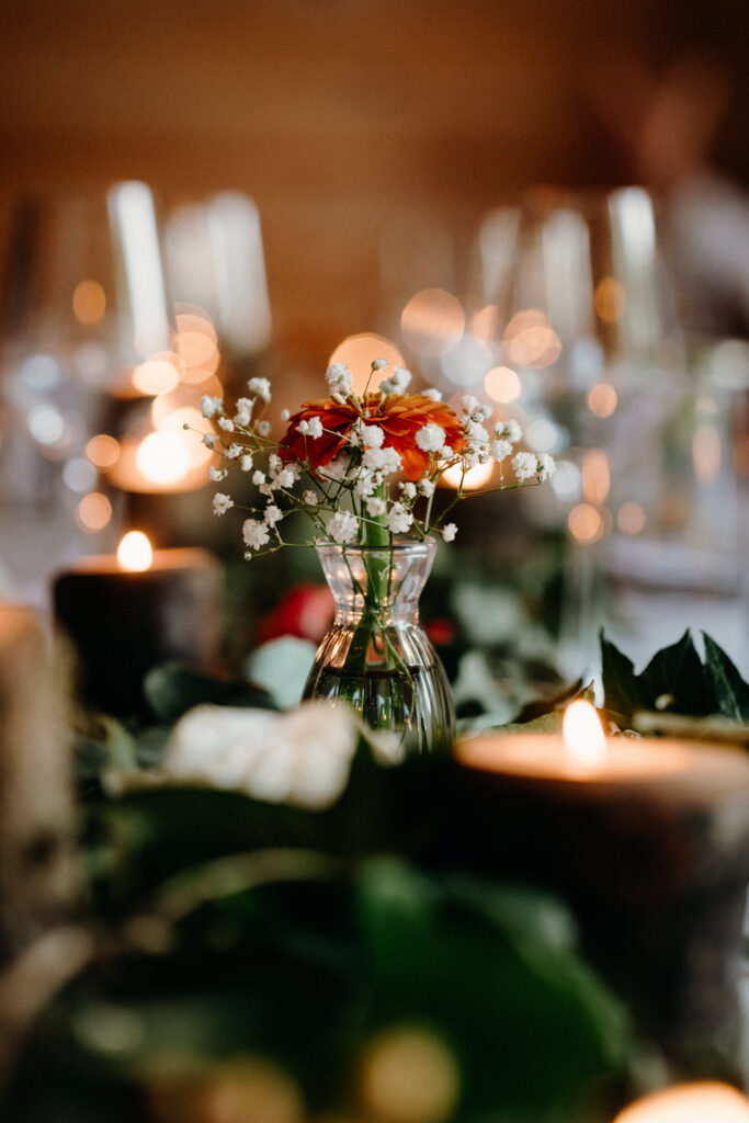 Reception table dressed with a greenery runner, pillar candles and roses