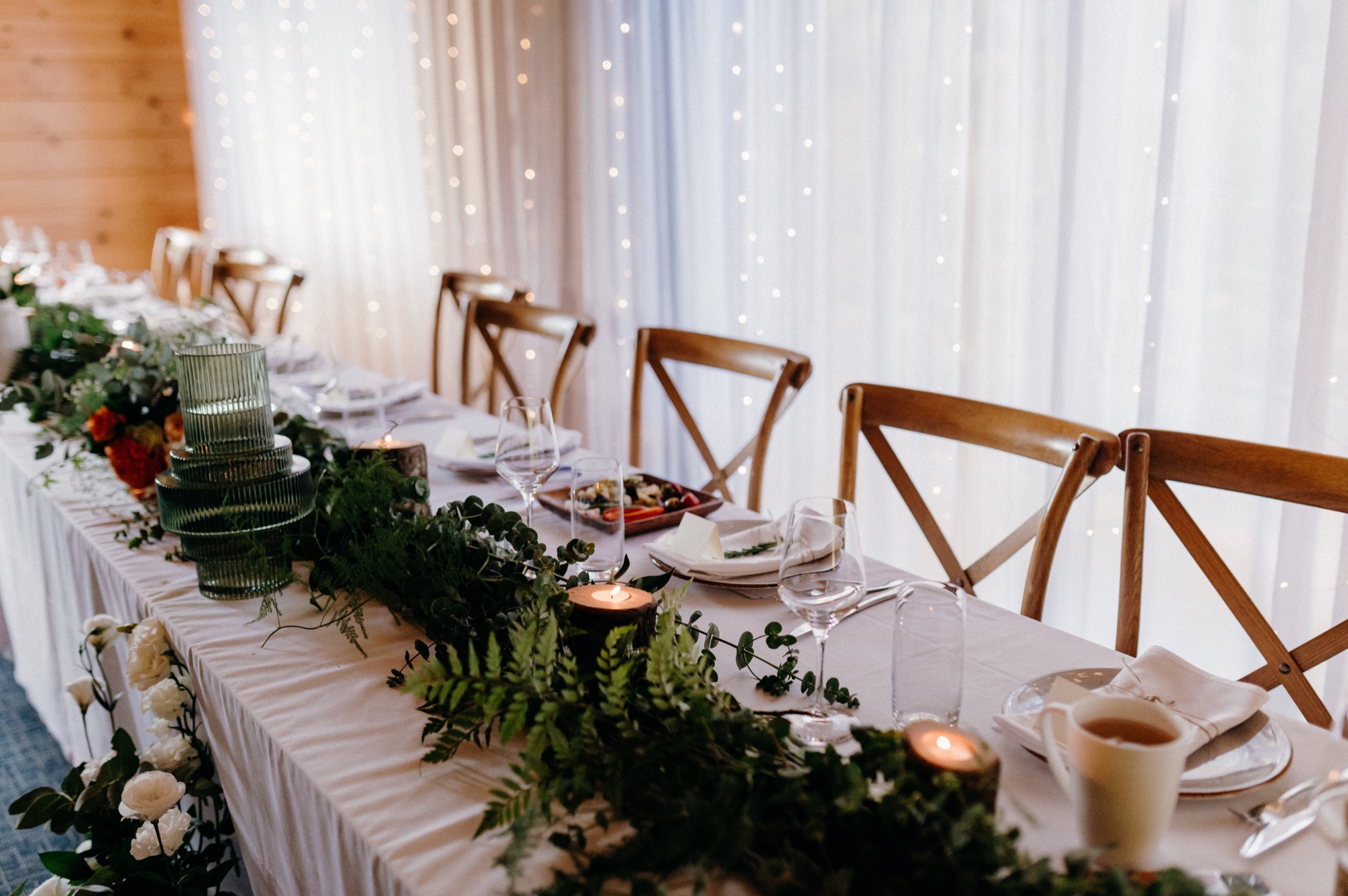 Long head table styled with a greenery runner and candles